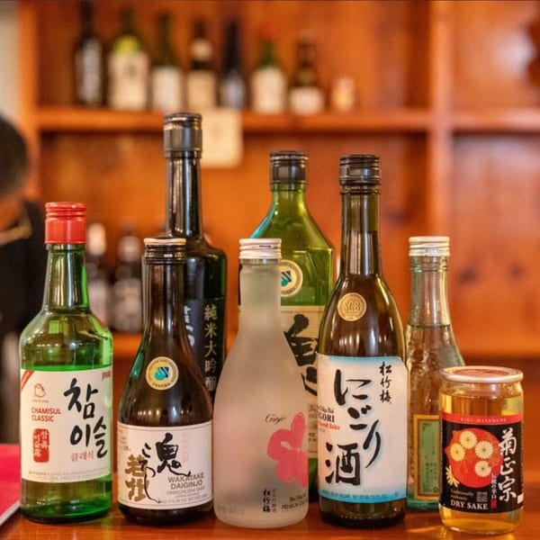 Assortment of sake and soju bottles, including Chamsul Classic, Wakatake Daiginjo, and Kiru Masamune Dry Sake.