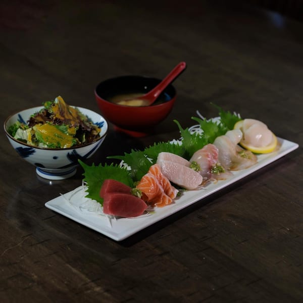 Sake Sushi sashimi platter with tuna, salmon, and other fish, alongside a salad and miso soup.